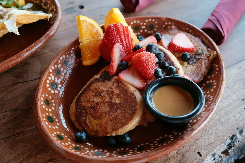 A plate of Concha French Toast with strawberries and blueberries.
