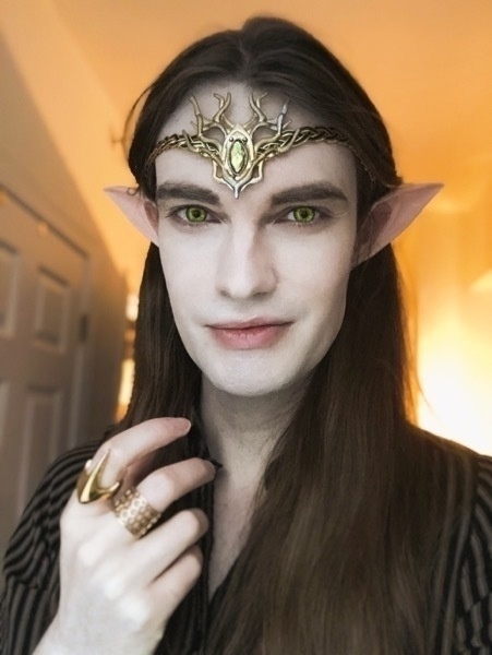 Hunter wearing elf ears, bright green contacts, a jeweled diadem, and two rings: one a honeycomb, the other a stinger