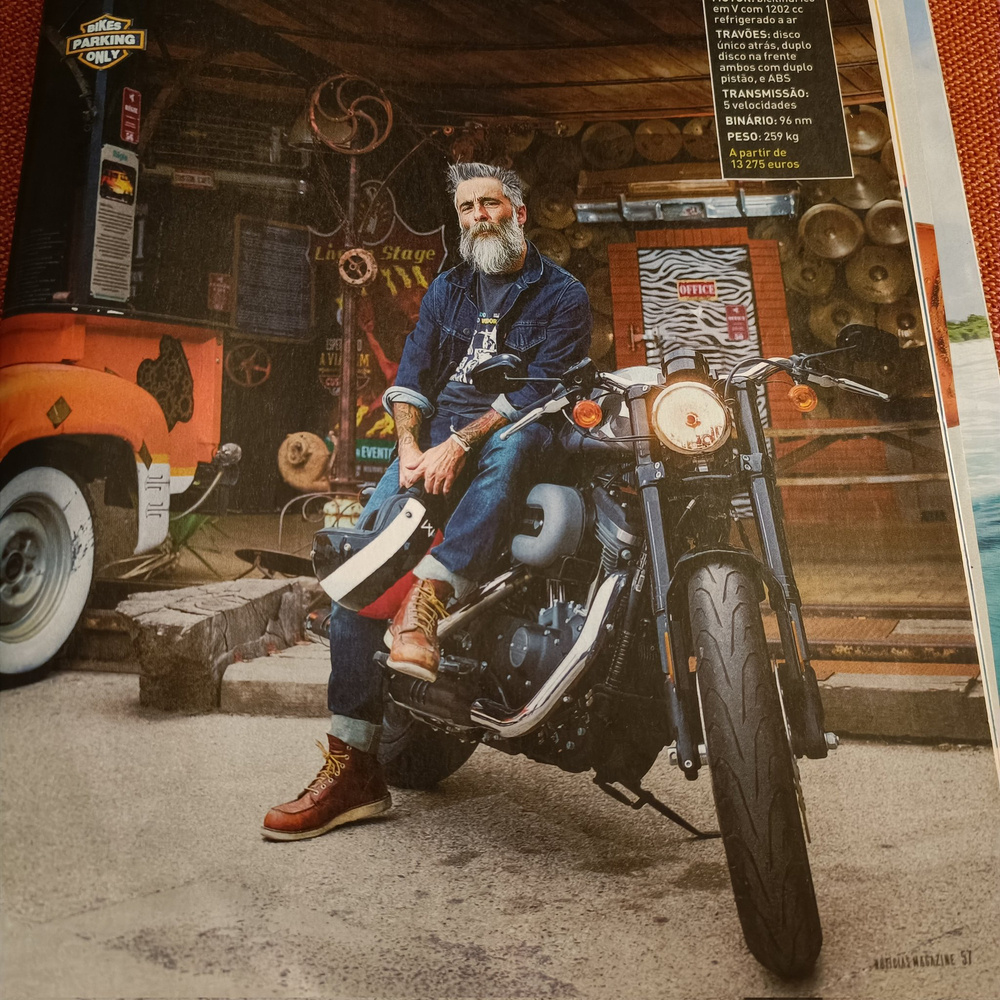 a man sits on a Harley motorcycle, in a magazine spread
