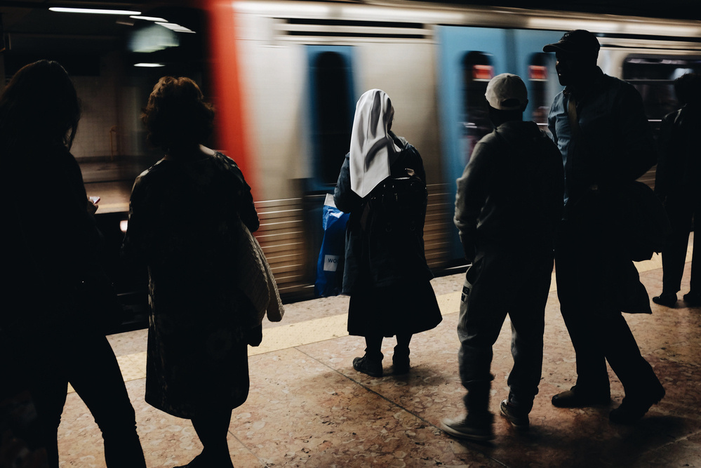 a nun waits at a busy subway station.