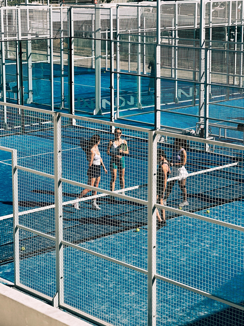 Four padel players on a blue court. 