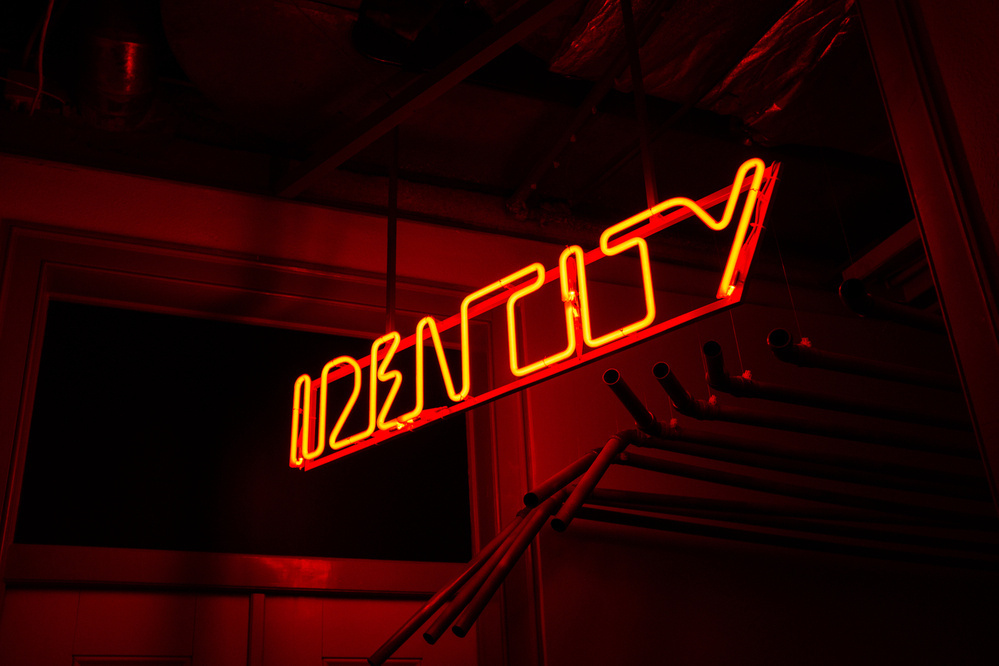“Identity” in red neon.