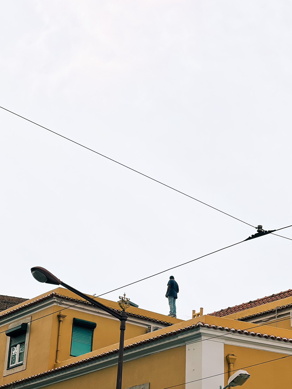 A man stands on the rooftop of a yellow building. 