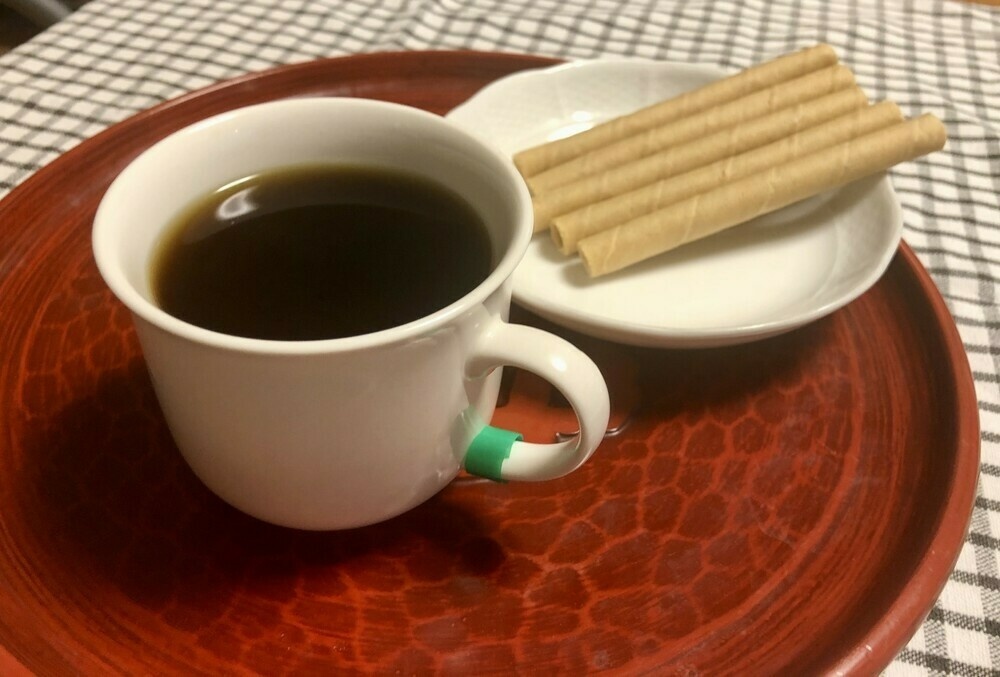 Cup of coffee with coconut crepes on a red lacquer tray.