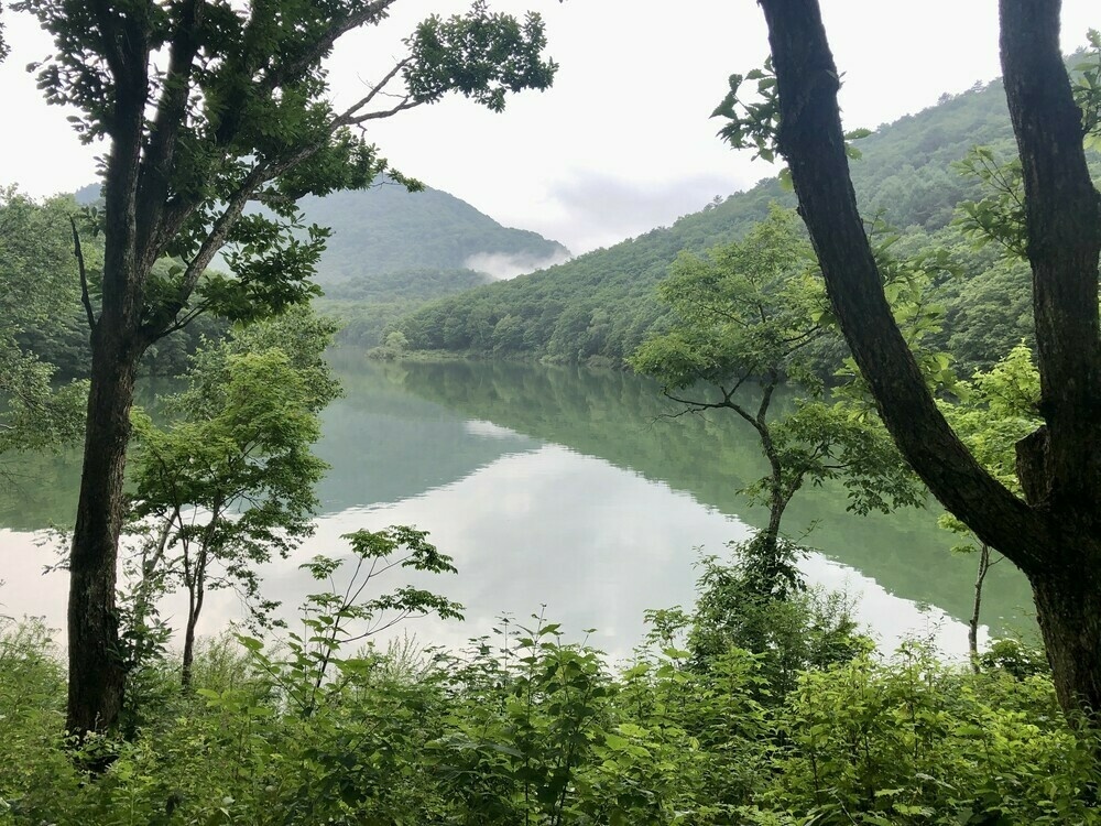 A high-elevation pond with mist covered mountaintops in distance