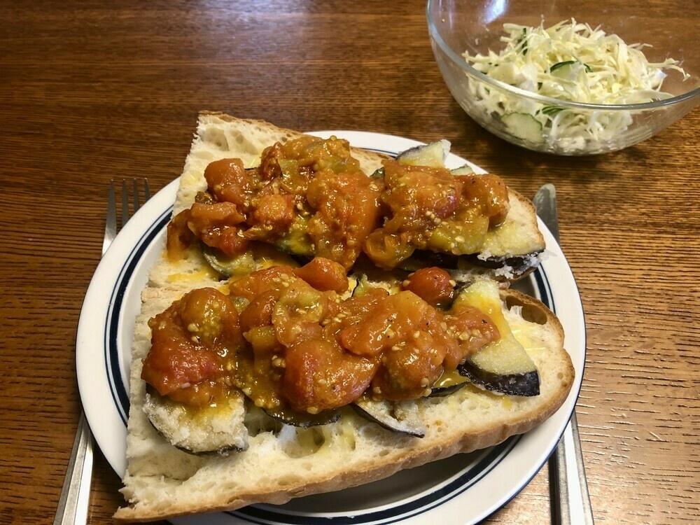 Open faced eggplant grinder on a bistro plate with Cole slaw in a glass bowl