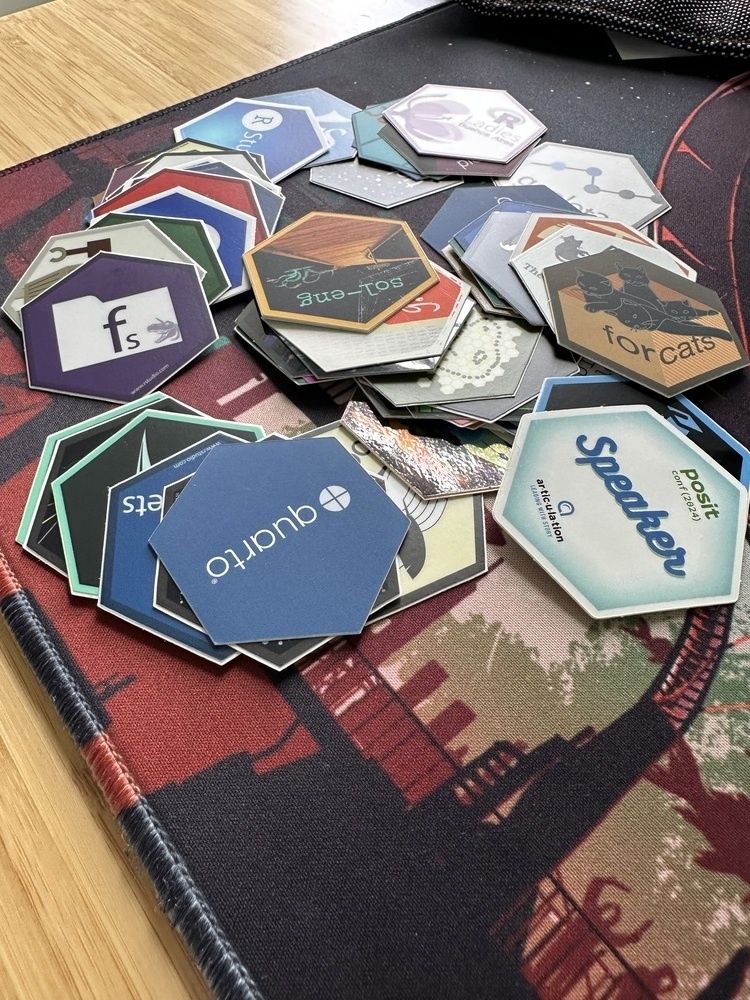 A pile of small hex-shaped stickers represeting R packages.