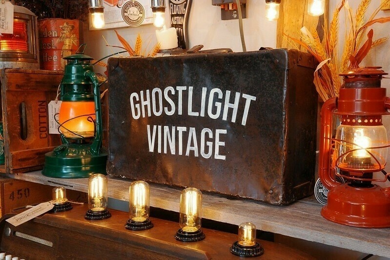 A display featuring vintage items, including two lanterns, various light bulbs, and a metal box labeled 