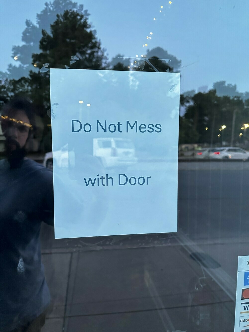 A glass door with a piece of paper taped to it that says “Do Not Mess with Door”.