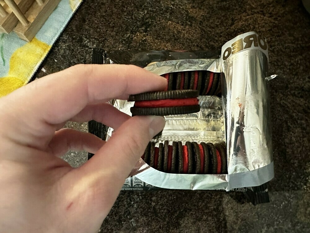 An open pack of Star Wars-themed Oreo. A hand is holding an Oreo with red cream.