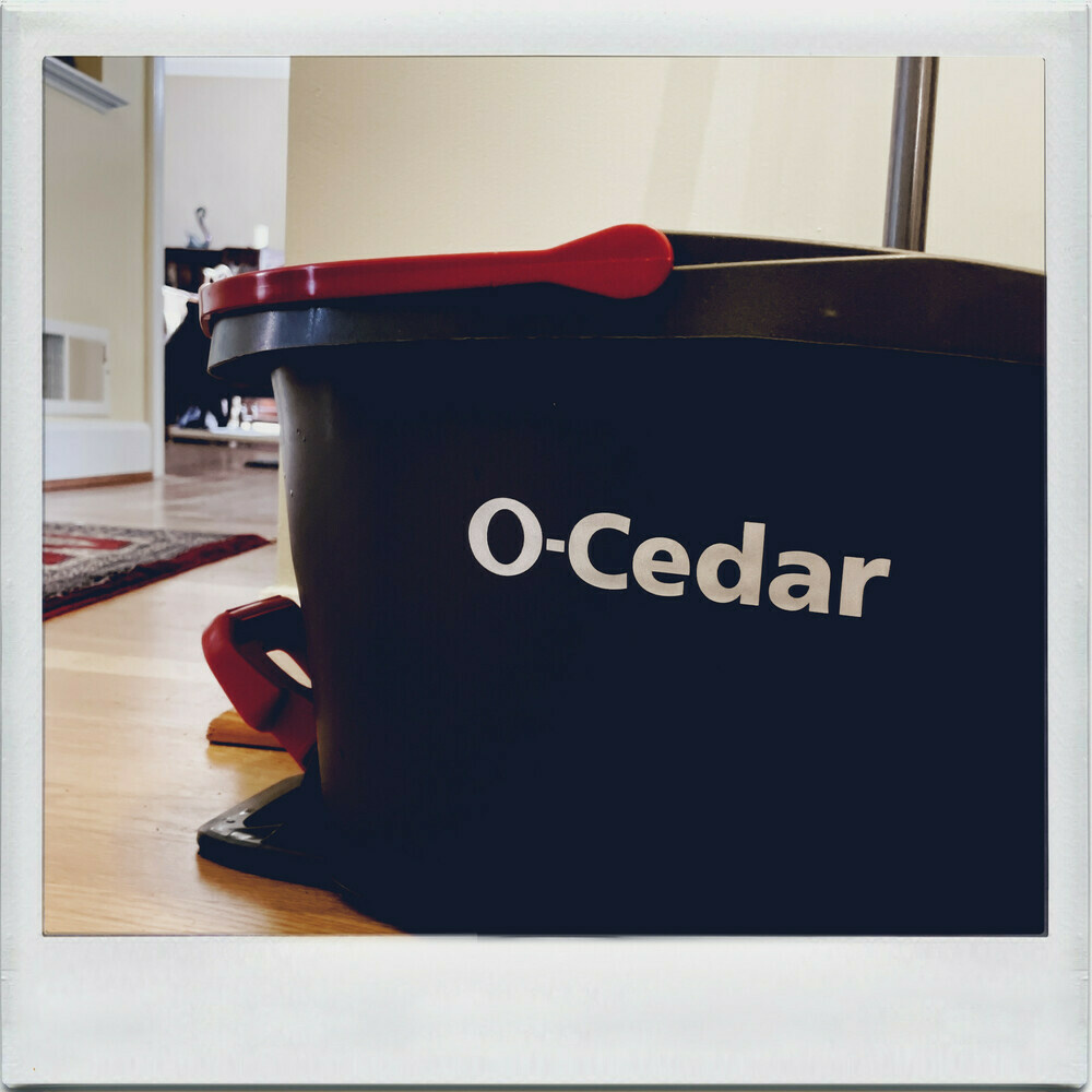 black mop bucket with a red handle and O-Cedar in white lettering