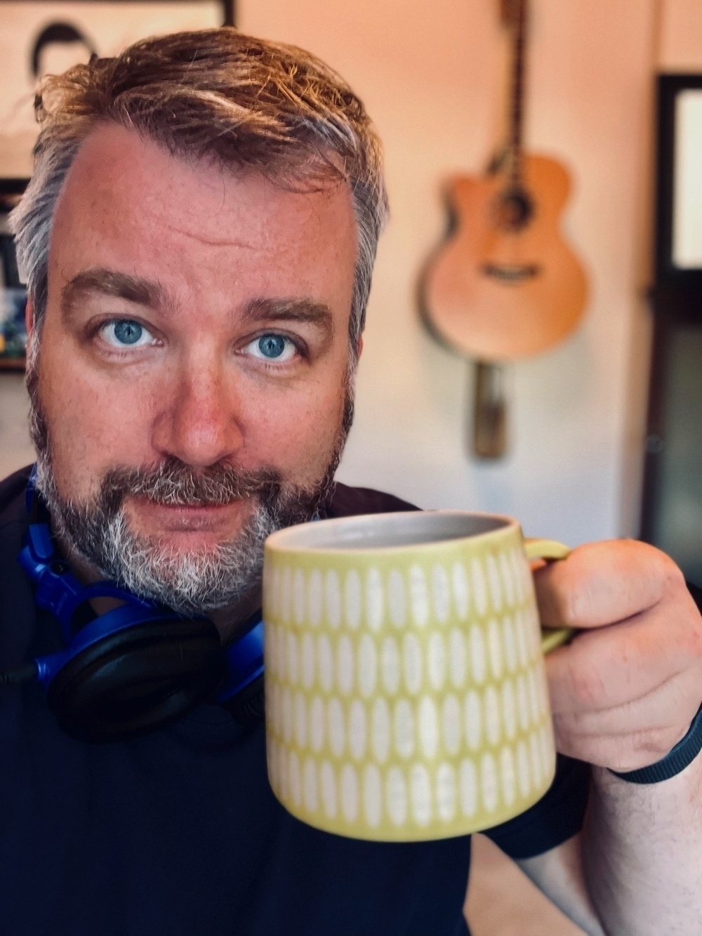 Chris holding a coffee mug and smiling at the camera.