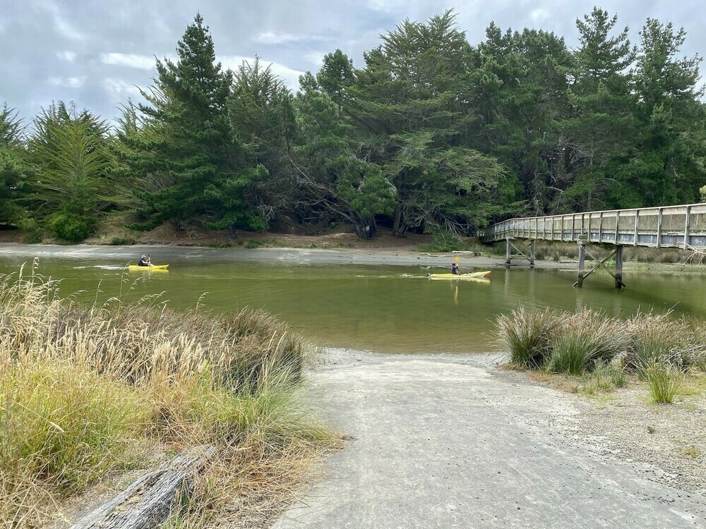 Two yellow kayaks on the river by the footbridge. 