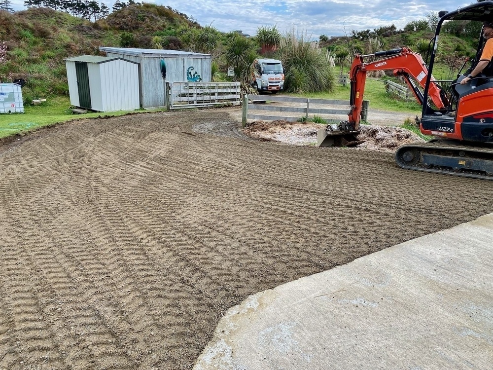 A fresh layer of shingle on the driveway, showing digger tread tracks. 