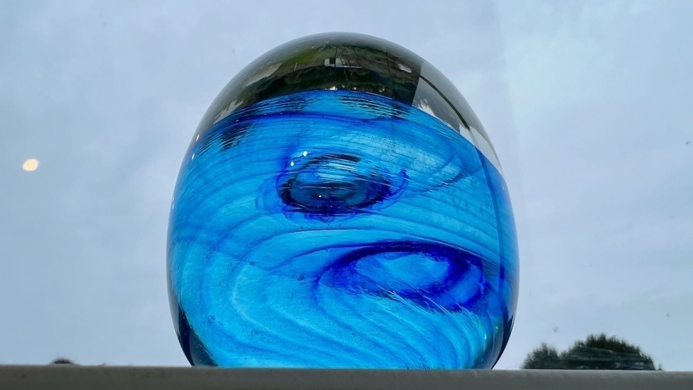 Glass paperweight with blue swirls. 