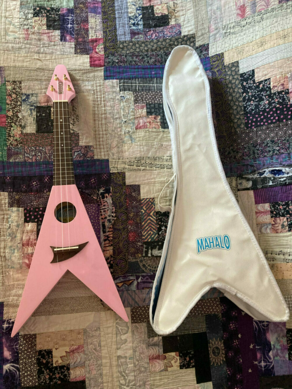 a bubblegum pink ukulele in a flying V shape, plus a matching carrying case