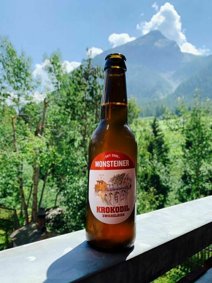 une biere rousse du nom de Krokodil de la brasserie Monsteiner de Davos. Sur l'étiquette figure une locomotive Crocodile. En arrière plan, les montagnes du Parc Ela aux Grisons