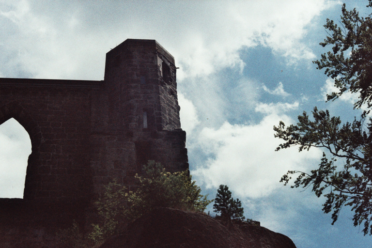 Ruins of a monastery, blue sky behind, a tree on the right.