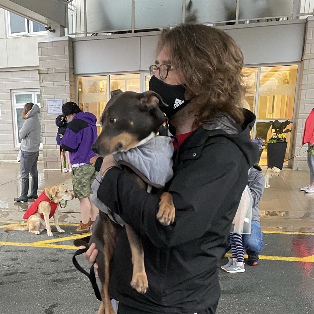 Luna being held in my arms while we stand with everyone and their dog outside our building