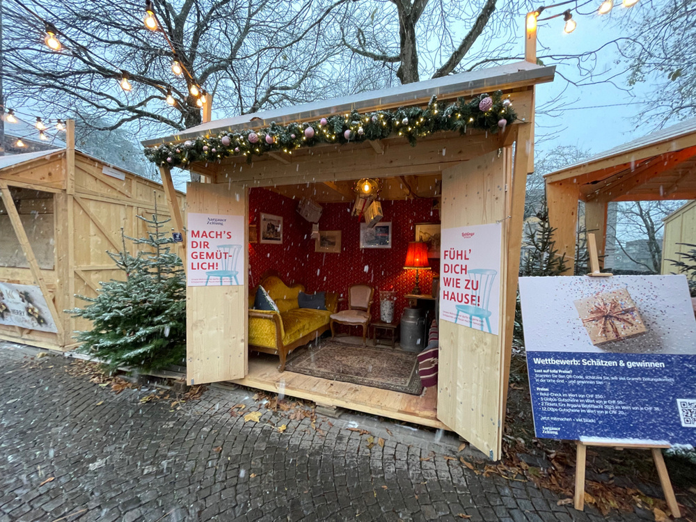 A stall at a Christmas market. Furnished as a break room. With inviting signs to sit down and rest. 