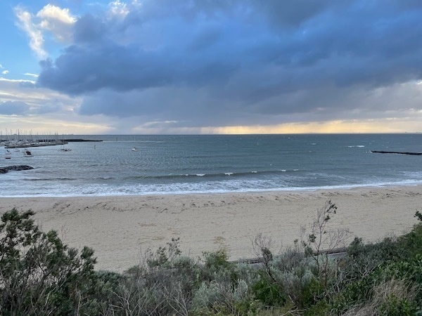 photo of a beach with partly cloudy skies above; coast at the bottom of frame