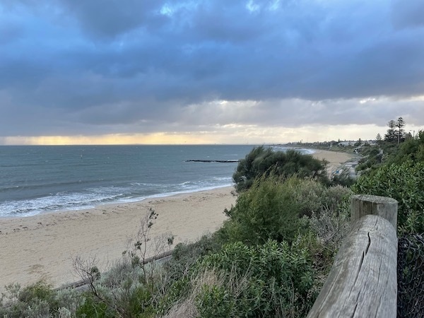 photo of a beach with partly cloudy skies above; coast on the right