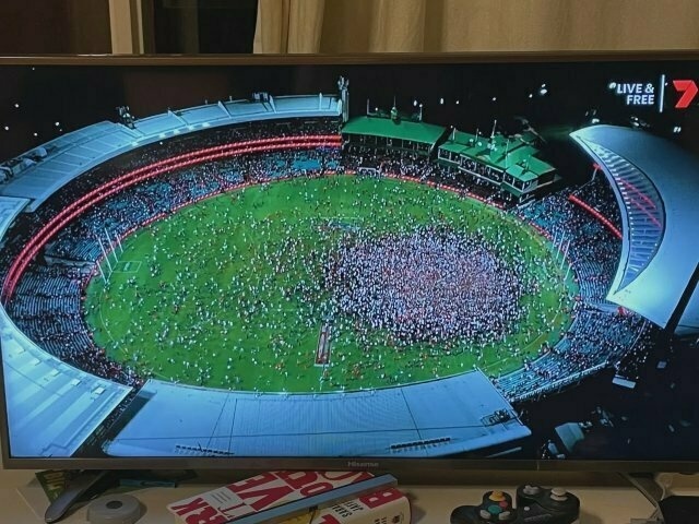 photo of a Channel 7 TV broadcast, showing tens of thousands of football fans pouring onto the SCG