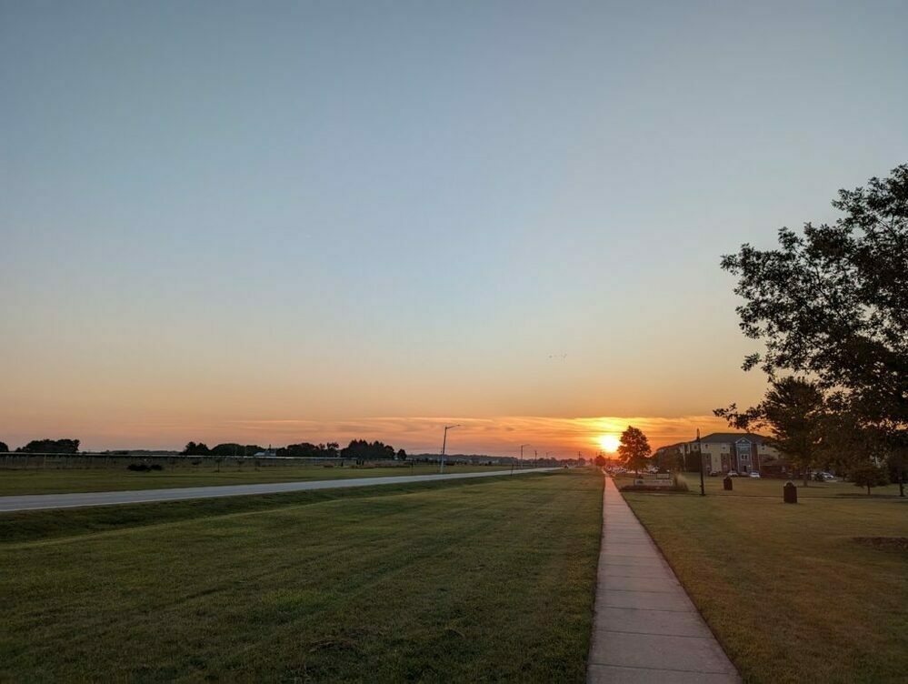 The sun rising right at the end of the sidewalk