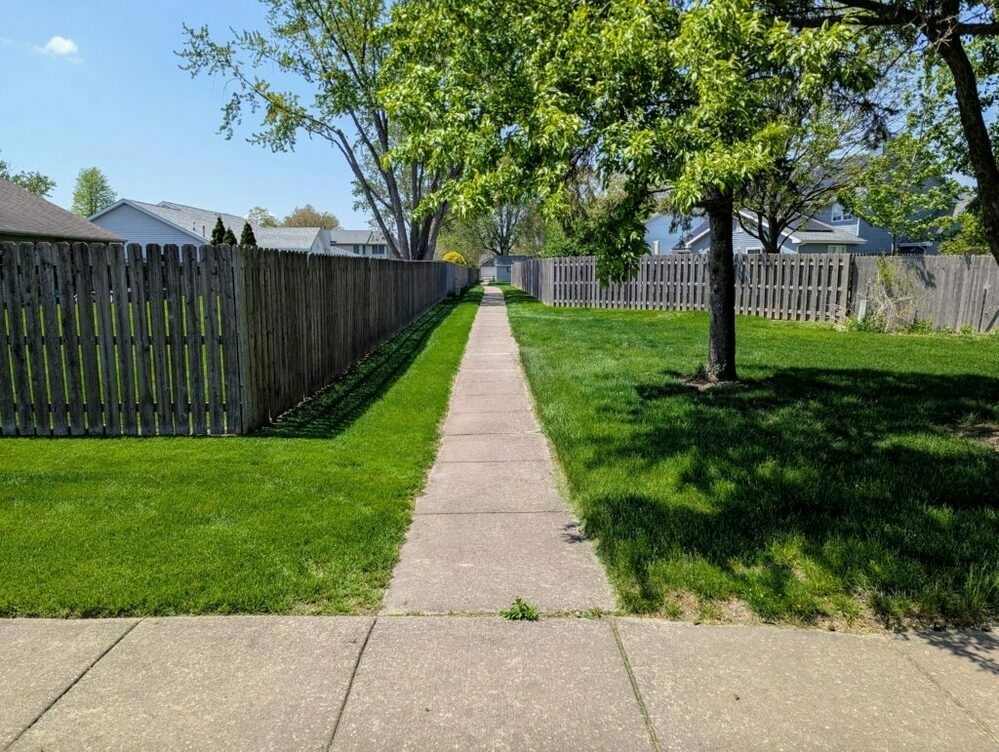 A suburban footpath running past backyard fences