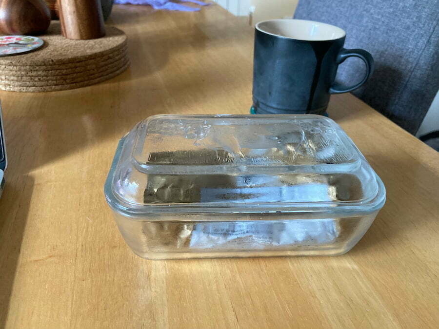 A glass butter dish on a table.