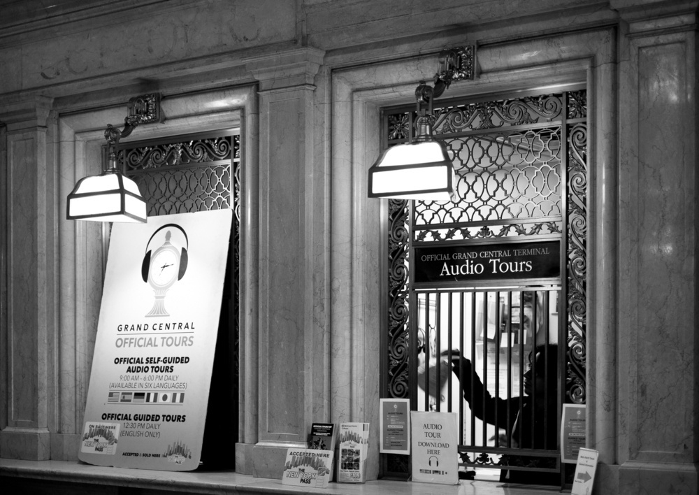 Black and white photo of the ticket window for Grand Central Station audio tours.