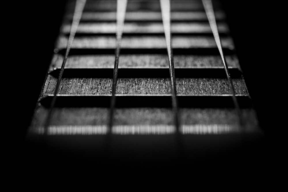 Black and white close-up photo looking down the neck of a ukulele.
