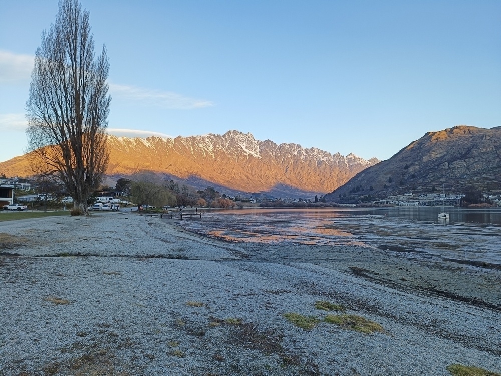 View across a lake with mountains in the background with afternoon sun shining.