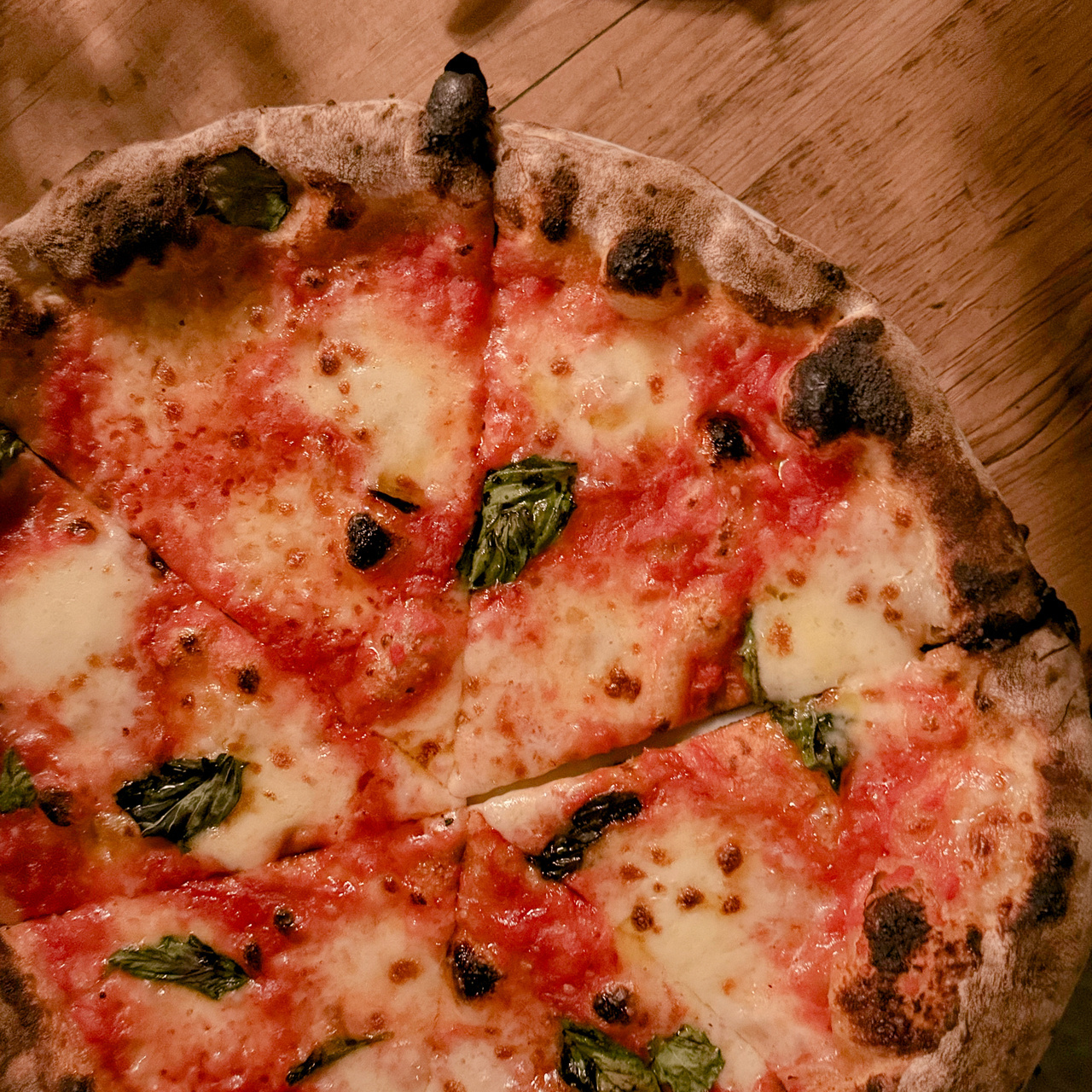 Margherita pizza with charred basil and dark crust