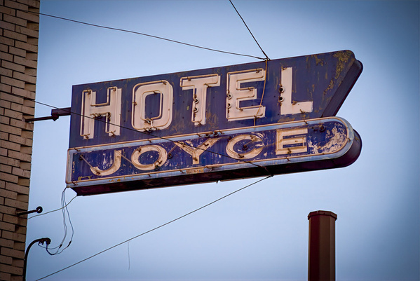 A vintage, weathered sign reads Hotel Joyce against a clear sky.